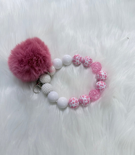 Pink and white beaded keychain bracelet with a large pink pom-pom and a silver key ring